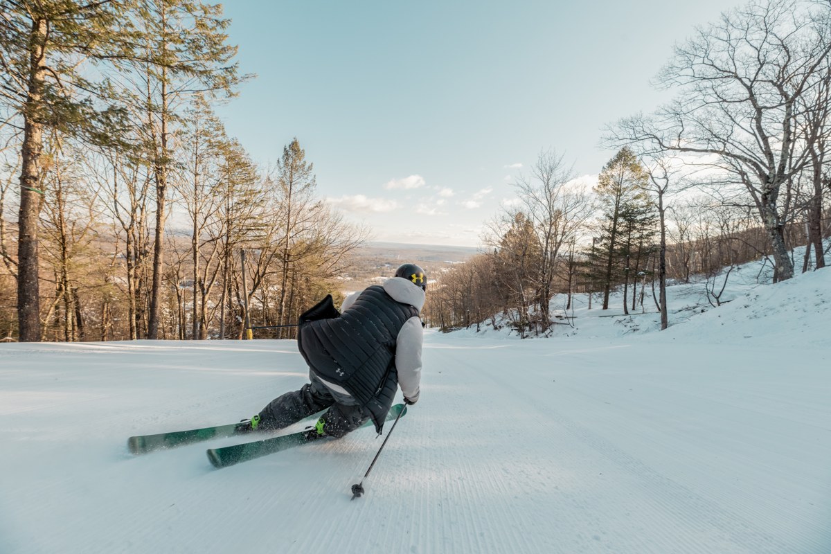Skier carving down a wooded slope at Camelback Mountain