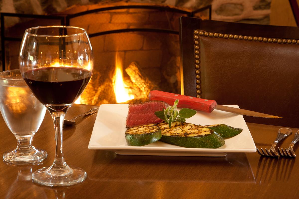 Steak dinner and wine beside the fireplace at The Frogtown Chophouse